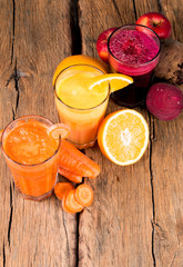 Fresh juices, orange, beetroot and carrot on wooden table 