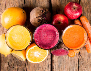 Fresh juices, orange, beetroot and carrot on wooden table 