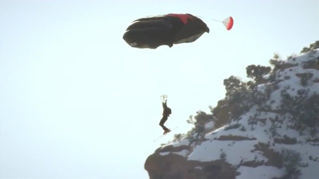 Base jumper soaring through the air wearing skis in slow motion.