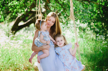 Mom hugging two daughters outdoors, family, childhood, family values, life style