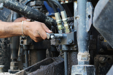 heavy equipment mechanic repairing hydraulic hoses