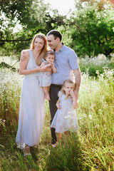 Mom and dad playing on the nature and hugging two daughters, family, childhood, family values, life style