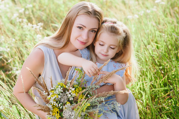 Mom and daughter in nature with a bouquet of wild flowers, family, family values, childhood, lifestyle