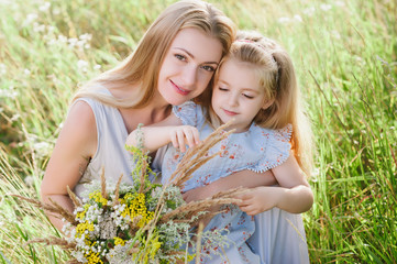 Mom and daughter in nature with a bouquet of wild flowers, family, family values, childhood, lifestyle