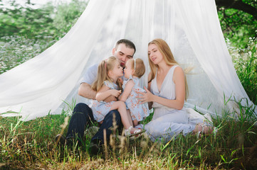 Mom and dad playing on the nature and hugging two daughters, family, childhood, family values, life style