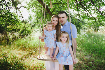 Mom and dad playing on the nature and hugging two daughters, family, childhood, family values, life...