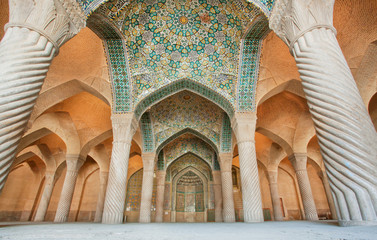 Persian patterns on the ceiling of mosque with columns and artworks, Iran