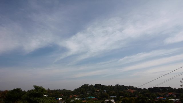 timelapse of landscape in thailand, hills with houses with cloudy blue sky