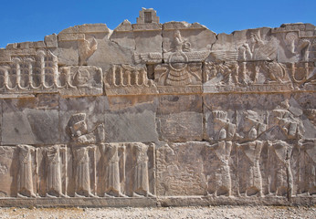 Fototapeta premium Scene with Faravahar - relief of winged sun symbol of Zoroastrianism in ruined Persepolis
