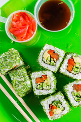 meatless vegetable sushi on a green plate with chopsticks, sauce