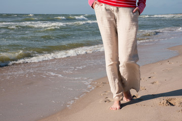 Woman in linen pants walking on the sea