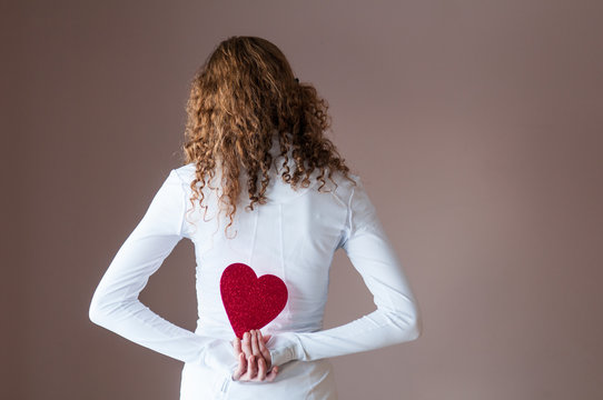 Teenage Girl Holding A Red Paper Heart Behind Her Back