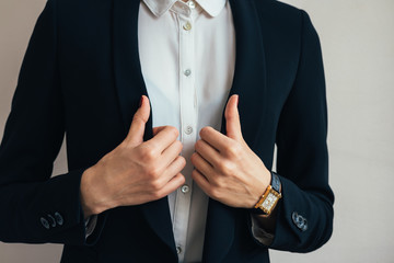 Woman wears a business suit jacket. In her hand wristwatch