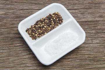 Black pepper and salt on wooden background