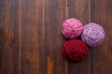 Three skeins in red and pink tones over wooden background