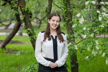 Girl schoolgirl walks in the lush spring garden after school