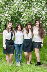 four girls graduate walk in the lush spring garden after school