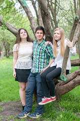 Three young friends happy graduates posing in the summer park