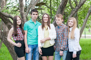 Five young friends happy graduates posing in the summer park