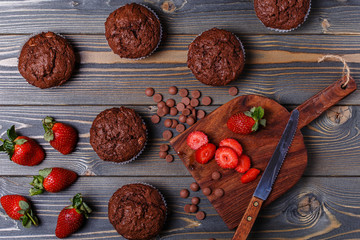 Chocolate muffins with strawberry on dark background.
