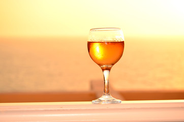 white wine glasses in front of the setting sun.Sea background