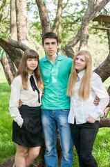 Three happy young friends hugging and laughing in the summer park