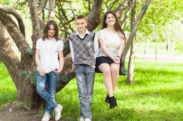 Three happy friends boy and two girls walking in the park
