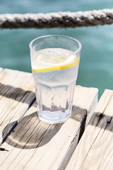 Gin tonic cocktail with lemon slice on a sea background