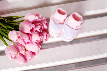 Anticipation. Pink baby boots with tulips