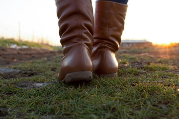 Beige boots outdoor, on green grass at sunset
