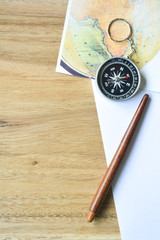 Compass on map, paper and wooden background.