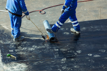 Professional installation of waterproofing on the concrete foundation. Two worker at construction...