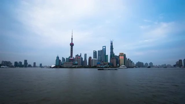 Wide time lapse of boats floating by with towers in the back in Shanghai China, at sunset.