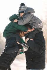 Cute young family with twins and pregnant young mother having fun in winter park on a bright day hugging each other and smiling
