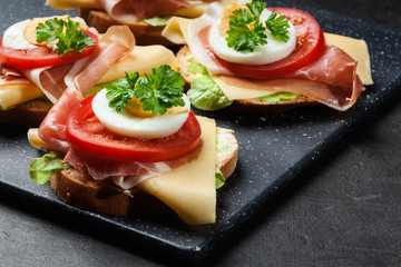 Fototapeta na wymiar Delicious sandwich with prosciutto ham, cheese, tomato and egg