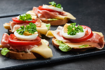 Delicious sandwich with prosciutto ham, cheese, tomato and egg