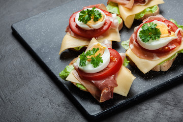 Delicious sandwich with prosciutto ham, cheese, tomato and egg