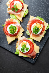Delicious sandwich with prosciutto ham, cheese, tomato and egg