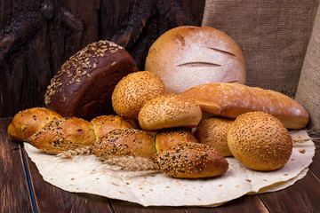 Assortment of baked bread and wheat on the wooden table