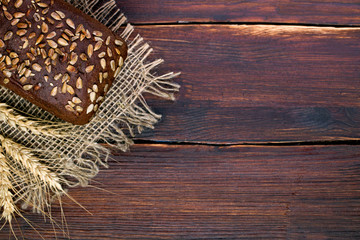 Black grain bread and wheat on the wooden