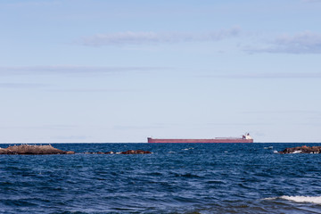 Great Lakes Freighter Passing Behind Rocky Outcroppings