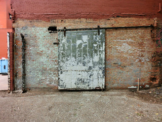 Heavy industrial door against old brick wall