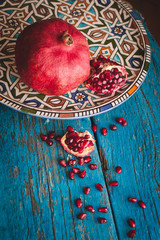 red ripe pomegranate in dish oriental style with copy space on w