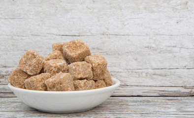 Sugarcane sugar cube in white bowl over wooden background