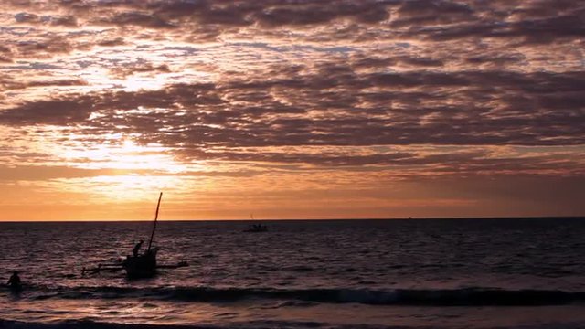 Colorful sunset overlooking the ocean as sail boats are floating in the water.