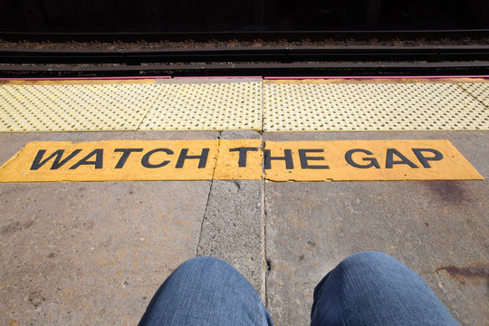 Railroad warning watch the gap with legs of commuter visible