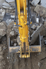 Yellow excavator removes dirt, asphalt and gravel on construction site. 