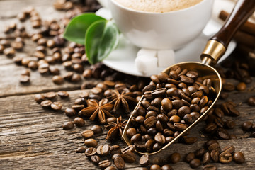 Close-up of coffee cup with roasted coffee beans on wooden backg