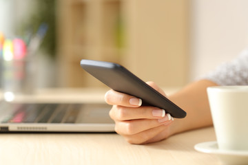Fototapeta premium Woman hand using a smart phone on a desk