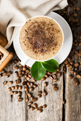 Close-up of coffee cup with roasted coffee beans on wooden backg